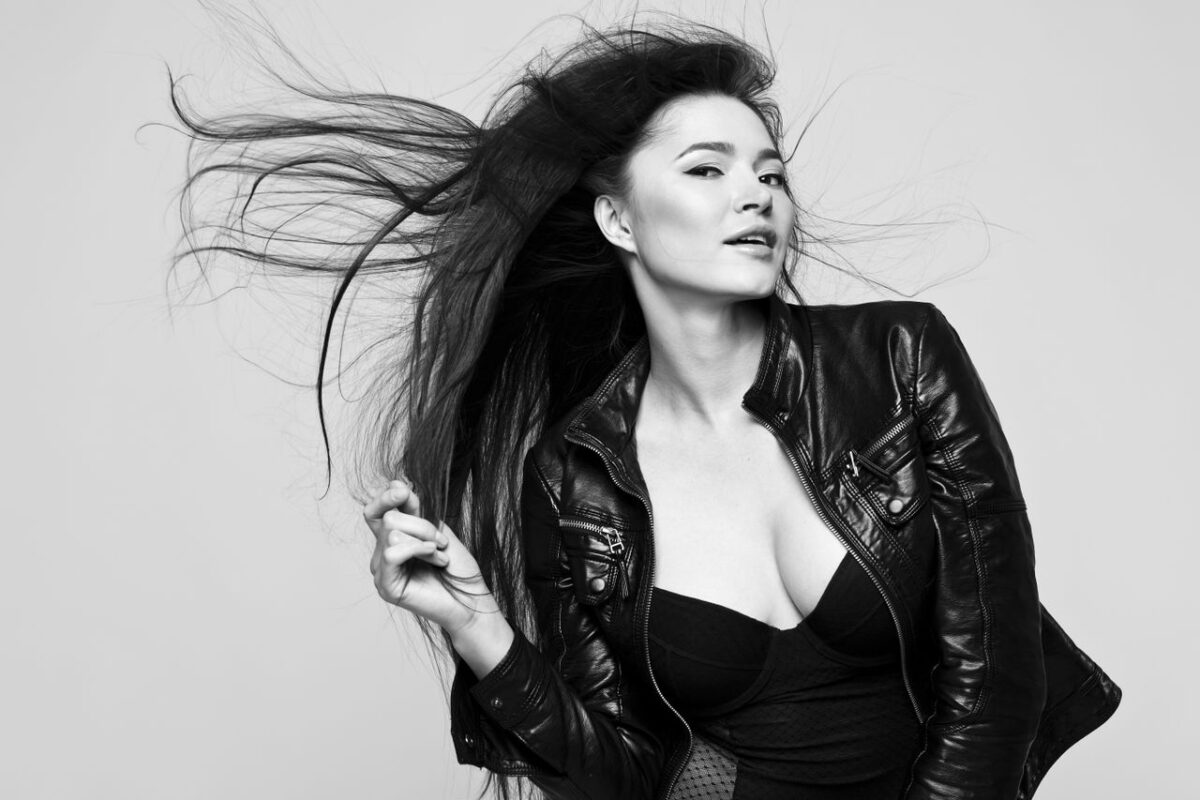 Elegant black and white portrait of a woman with flowing hair in a leather jacket.